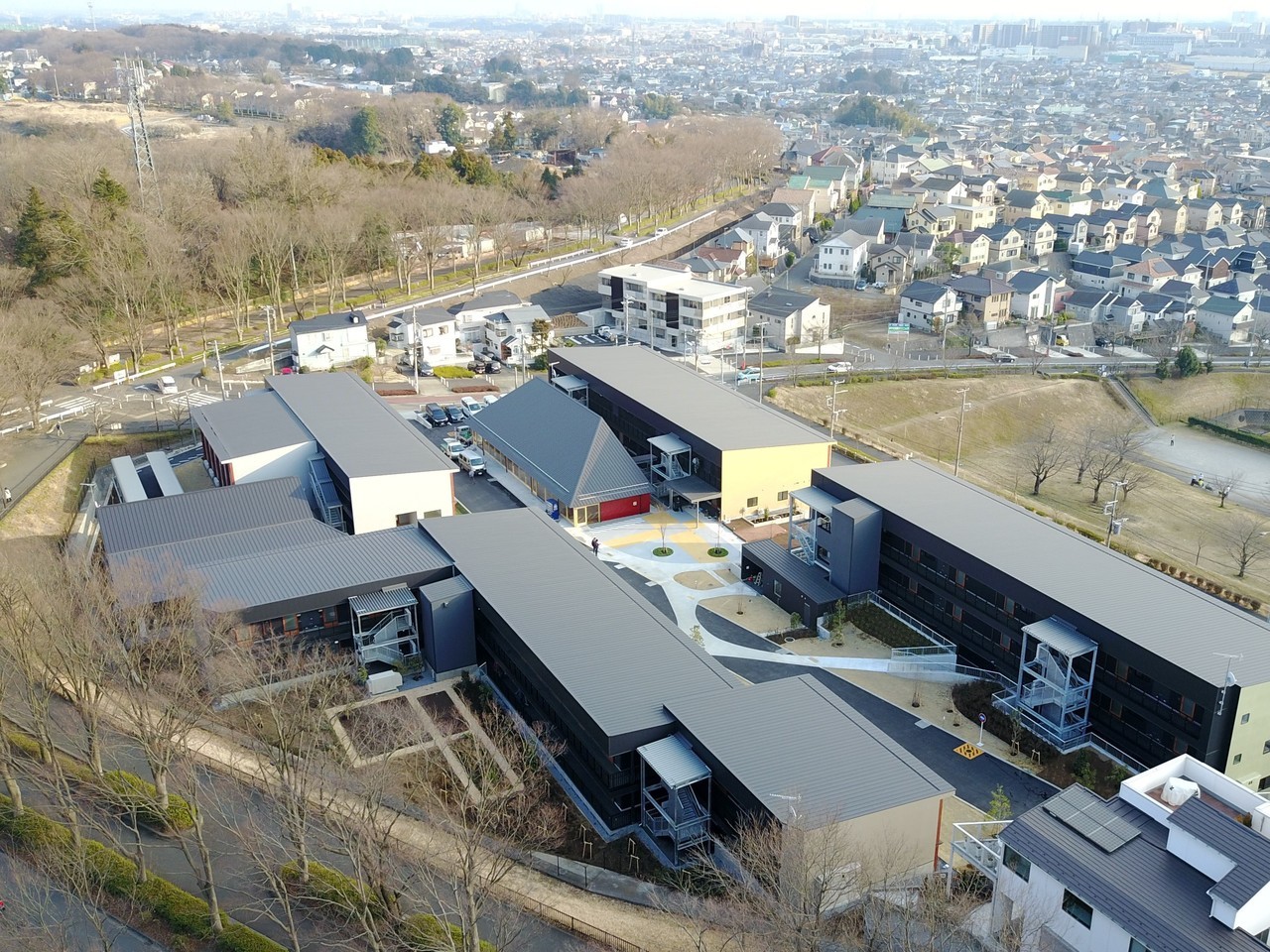 介護施設の全体俯瞰。複数棟の建物と周辺の住宅地が見える。